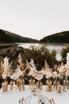 the table is set with flowers, candles and silverware for an outdoor wedding reception