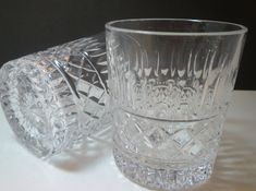 two clear glass tumblers sitting on top of a white table next to each other