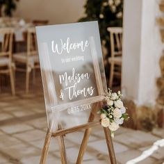 a welcome sign with flowers on it sitting in front of a stone wall and floor