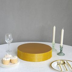 a table topped with a cake and cupcakes on top of a white table cloth