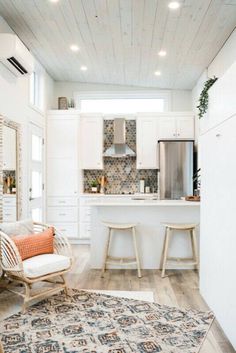 a kitchen with white cabinets and an area rug in front of the stove top oven