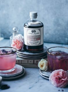 a bottle of gin on top of a table next to two glasses and a book