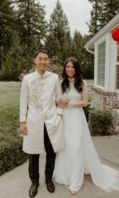 a man and woman standing next to each other in front of a house with red lanterns