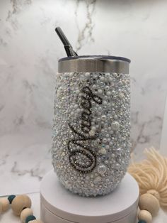 a cup that is sitting on top of a stand with beads and a toothbrush in it