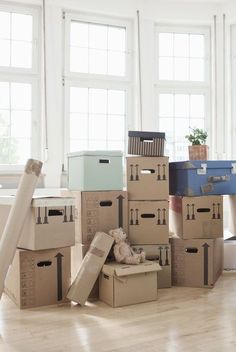 several boxes stacked on top of each other in an empty room with windows and wooden floors