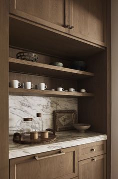 a kitchen with wooden cabinets and marble counter tops in the center, along with dishes on shelves