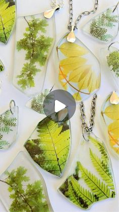 several leaf shaped glass pendants on a white background with the image of trees and leaves painted on them