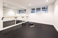 an empty room with mirrors and exercise equipment on the floor in front of it,