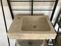 a stone sink sitting on top of a wooden floor next to a metal rack with bottles