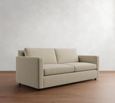 a couch sitting on top of a hard wood floor next to a white wall in an empty room