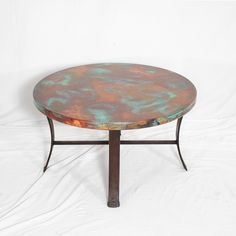 a round metal table sitting on top of a white surface with green and orange paint