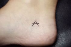 a small triangle tattoo on the side of a person's foot, with an arrow in it