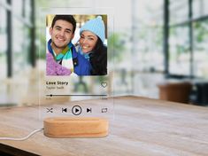 an image of a couple on the screen of a cell phone that is sitting on top of a wooden table