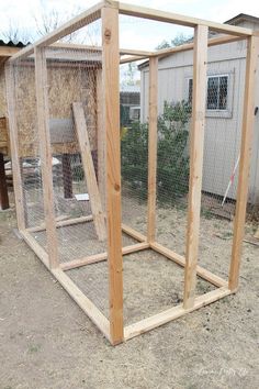 a chicken coop in the middle of a yard next to a building with a fence around it