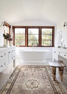 a bathroom with a rug, sink and bathtub in the middle of the room