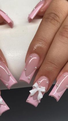 a woman's nails with pink and white designs on them, one has a bow