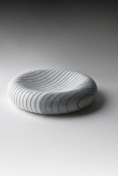 a white bowl sitting on top of a gray floor next to a black and white wall