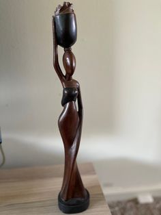 a wooden statue holding a candle on top of a table