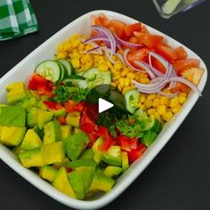 a white bowl filled with vegetables on top of a black table next to a green and white checkered napkin