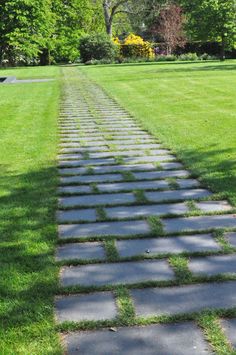 a stone path in the middle of a grassy field