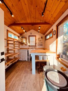 the inside of a tiny house with wood flooring and wooden walls, windows, and shelves