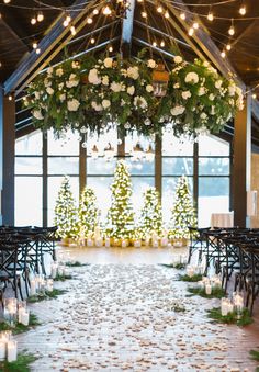 an indoor wedding venue with candles and greenery on the aisle, decorated with white flowers