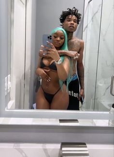 a man and woman taking a selfie in front of a bathroom mirror