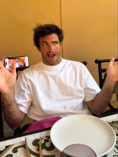 a man sitting at a table holding up his cell phone