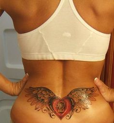 a woman's stomach with an angel wing tattoo on her lower back and side