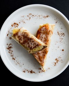 two pieces of food on a white plate with powdered sugar and cinnamon sprinkles