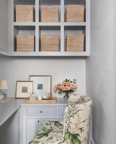 a white chair sitting in front of a desk with baskets on it's shelves