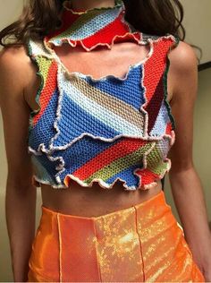 a woman wearing an orange skirt and a colorful crop top with ruffles on it