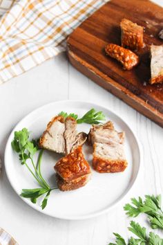 some meat is on a white plate and garnished with parsley next to a cutting board