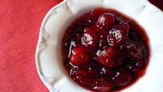 a white bowl filled with cherries on top of a red table