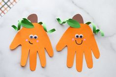 two handprinted oranges with green leaves on them