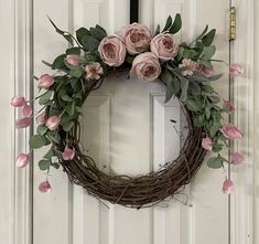 a wreath with pink flowers hanging on the front door