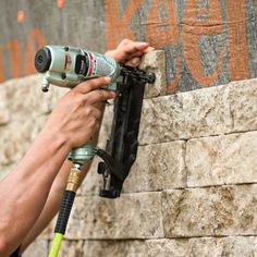 a man is using a power drill to fix a brick wall with a concrete block