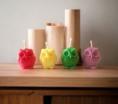 three colorful owls sitting on top of a wooden table next to candles and vases