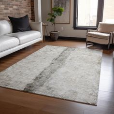 a living room filled with furniture and a large rug on top of a hard wood floor