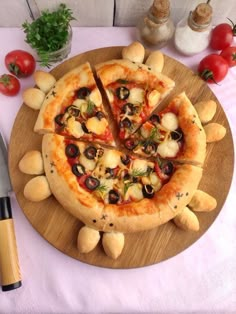 a pizza sitting on top of a wooden plate covered in cheese and toppings next to a knife