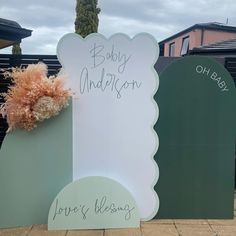 a baby announcement sign sitting on the side of a building next to a potted plant