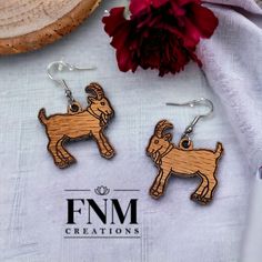 the wooden earrings are decorated with an image of two rams and one is holding a red flower