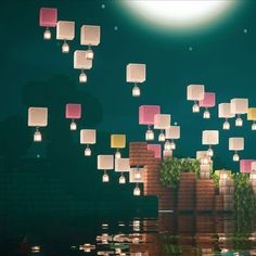 a bunch of lanterns floating in the air over water