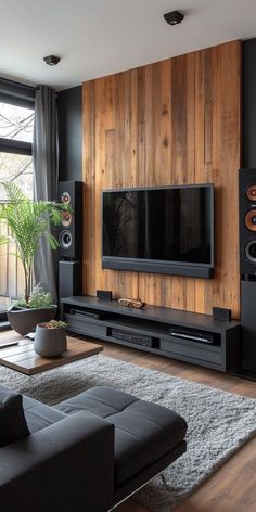 a living room with black furniture and wood paneling on the wall, large flat screen tv