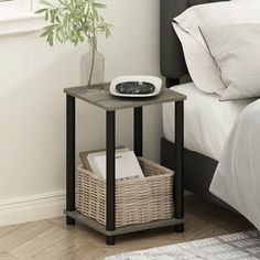 a small table with a basket on it next to a bed