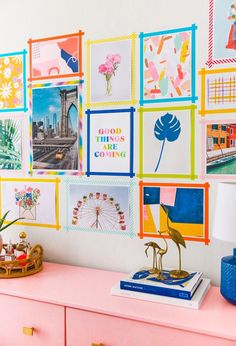 a pink dresser with pictures on the wall and a lamp sitting on top of it