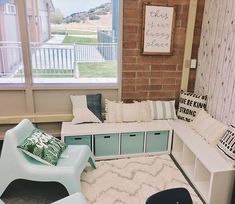 a living room filled with lots of furniture next to a brick wall covered in windows