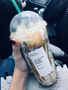 a person holding a drink in their hand while sitting in the backseat of a car