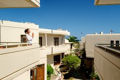 a man standing on the balcony of an apartment building looking out at the surrounding buildings