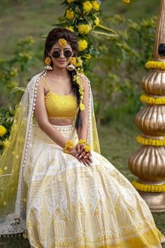 a woman in a yellow and white lehenga sitting on the ground next to flowers